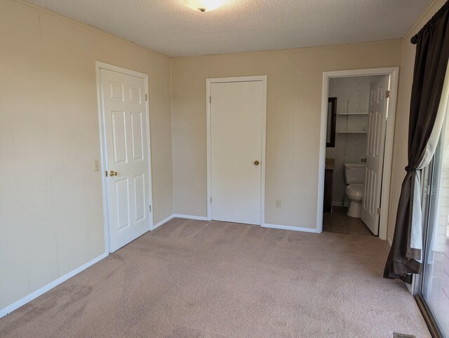 unfurnished bedroom with connected bathroom, carpet, and a textured ceiling