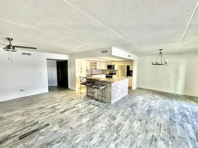 kitchen with light hardwood / wood-style flooring, stainless steel appliances, ceiling fan with notable chandelier, and white cabinetry