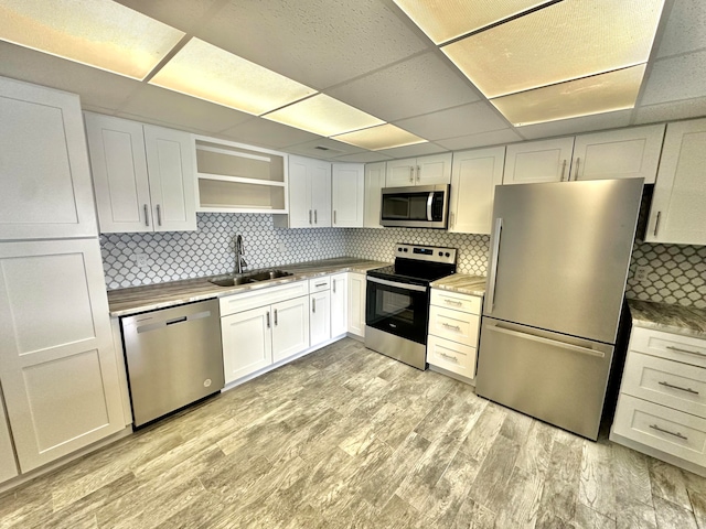 kitchen featuring white cabinets, light hardwood / wood-style flooring, stainless steel appliances, sink, and a paneled ceiling