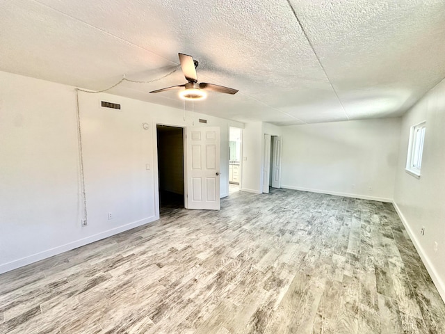 unfurnished room featuring a textured ceiling, ceiling fan, and light wood-type flooring