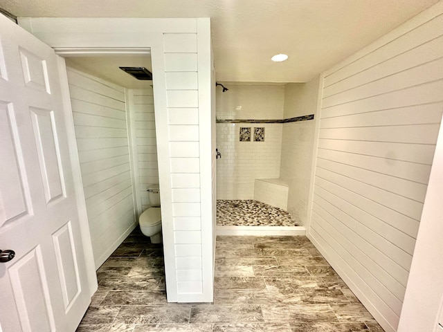 bathroom with toilet and a tile shower