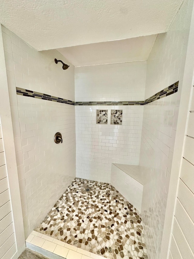 bathroom with a tile shower and a textured ceiling