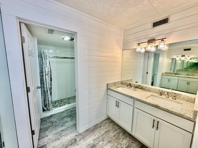 bathroom featuring a textured ceiling, vanity, a shower with shower curtain, wood walls, and hardwood / wood-style flooring