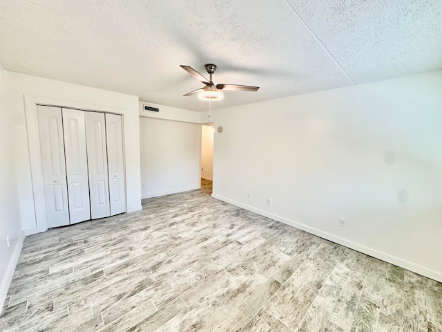 unfurnished bedroom featuring a textured ceiling, ceiling fan, a closet, and light wood-type flooring