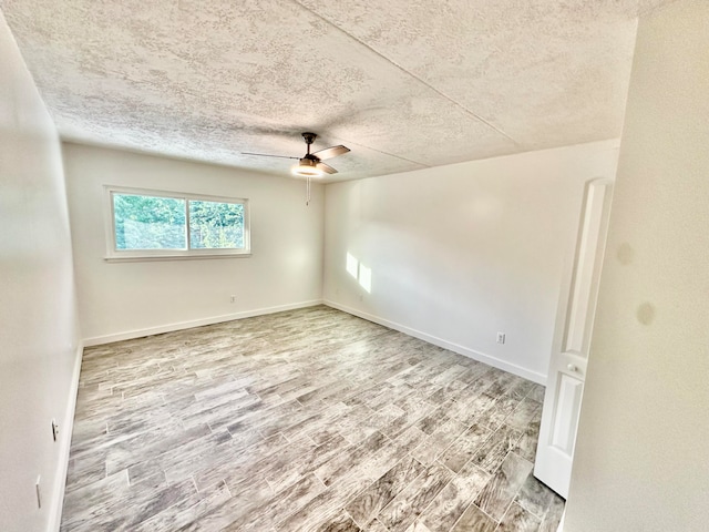 empty room with hardwood / wood-style floors, ceiling fan, and a textured ceiling