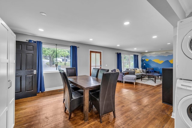 dining space with hardwood / wood-style floors and stacked washer / dryer