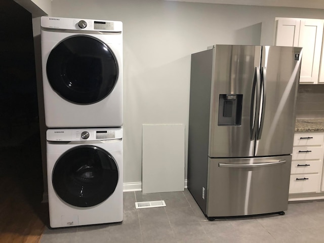 laundry area featuring stacked washer / drying machine and light tile patterned floors