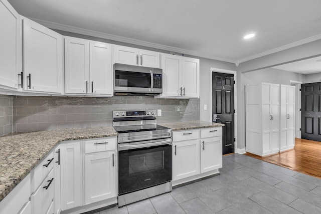 kitchen with white cabinetry, crown molding, light stone counters, and appliances with stainless steel finishes