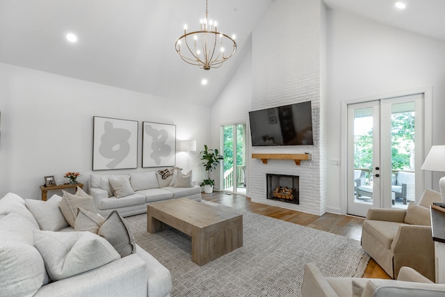 living room with a healthy amount of sunlight, high vaulted ceiling, light wood-type flooring, and a fireplace