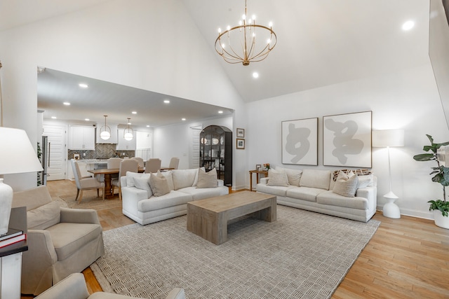 living room with high vaulted ceiling, light hardwood / wood-style floors, and a notable chandelier