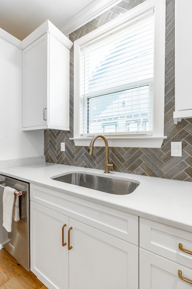 kitchen featuring dishwasher, light wood-type flooring, white cabinetry, sink, and tasteful backsplash