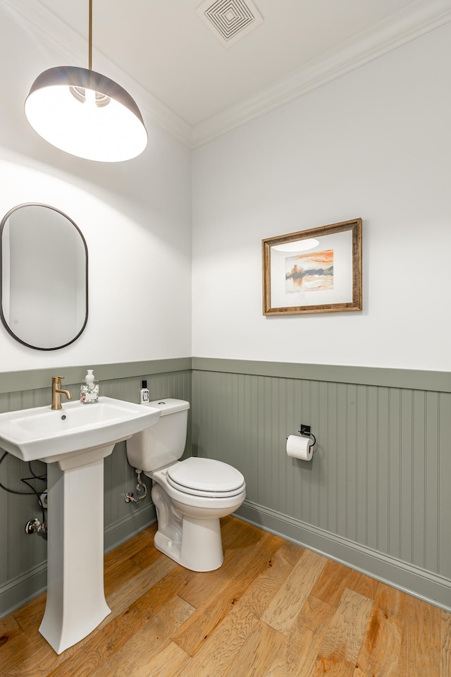 bathroom with toilet, ornamental molding, sink, and hardwood / wood-style flooring