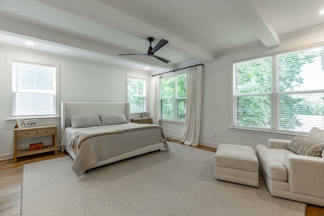 bedroom with ceiling fan, beamed ceiling, and light hardwood / wood-style flooring