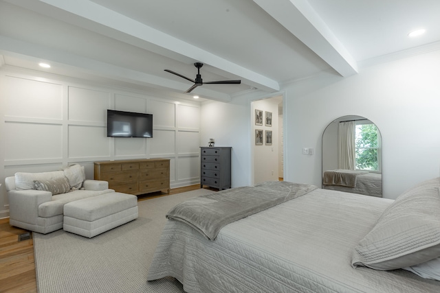 bedroom with ceiling fan, ornamental molding, light hardwood / wood-style floors, and beam ceiling