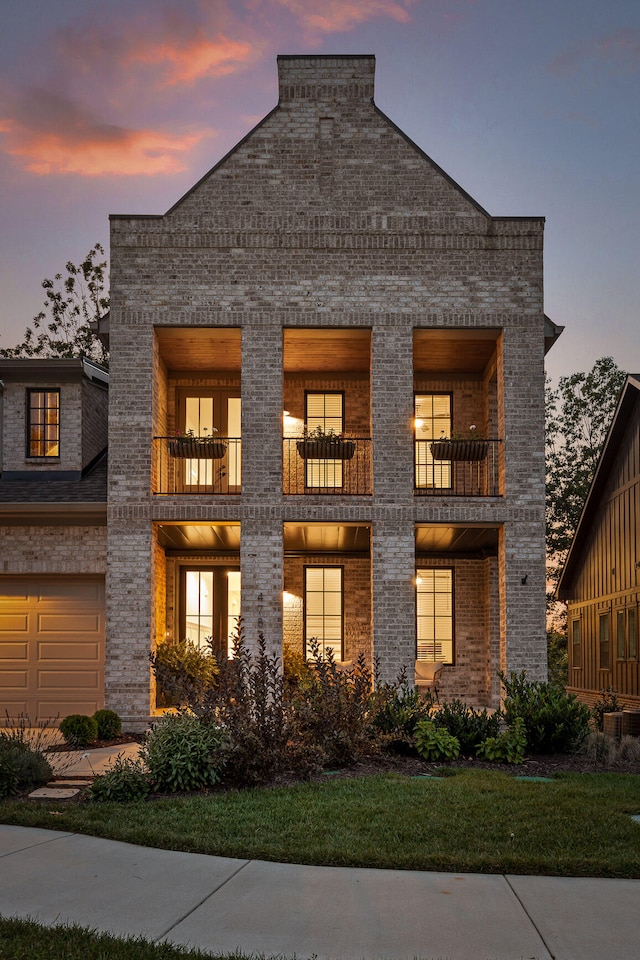 view of front of home with a yard, a garage, and a balcony