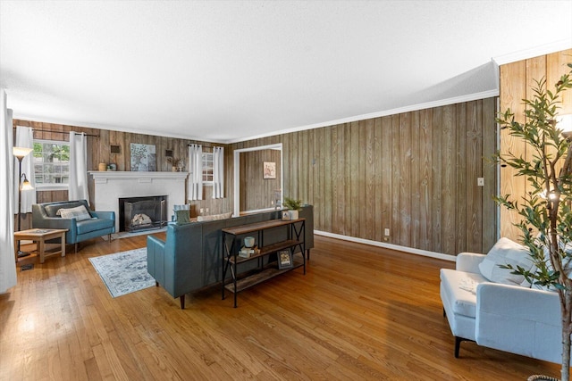 living room with crown molding, a textured ceiling, hardwood / wood-style flooring, and wooden walls