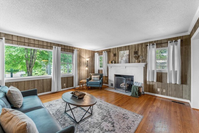 living room with a wealth of natural light, wood walls, ornamental molding, and hardwood / wood-style floors