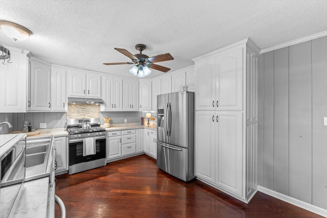 kitchen with ornamental molding, a textured ceiling, stainless steel appliances, ceiling fan, and dark hardwood / wood-style floors