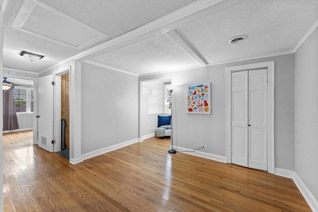 unfurnished bedroom featuring crown molding, a textured ceiling, and wood-type flooring