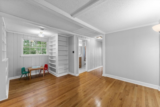 unfurnished room featuring a textured ceiling, hardwood / wood-style flooring, wood walls, and built in shelves