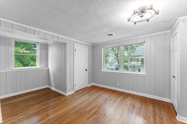 unfurnished bedroom featuring a textured ceiling, wood-type flooring, an inviting chandelier, and a closet