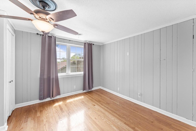 empty room with a textured ceiling, hardwood / wood-style floors, and ceiling fan