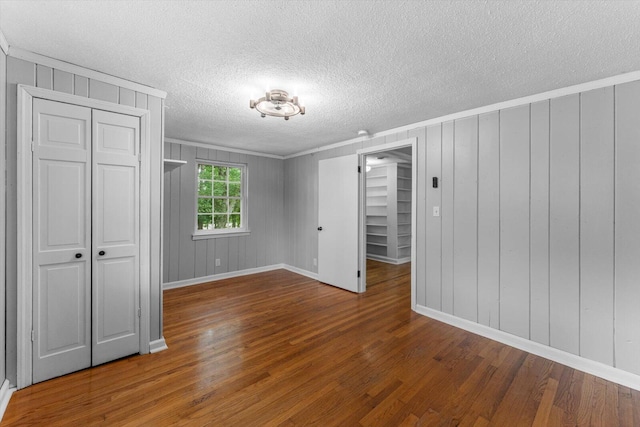 spare room featuring a textured ceiling, wood walls, and hardwood / wood-style floors