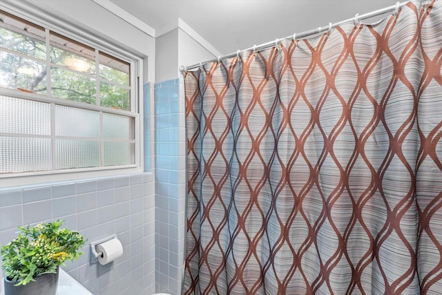 bathroom featuring tile walls, walk in shower, and ornamental molding