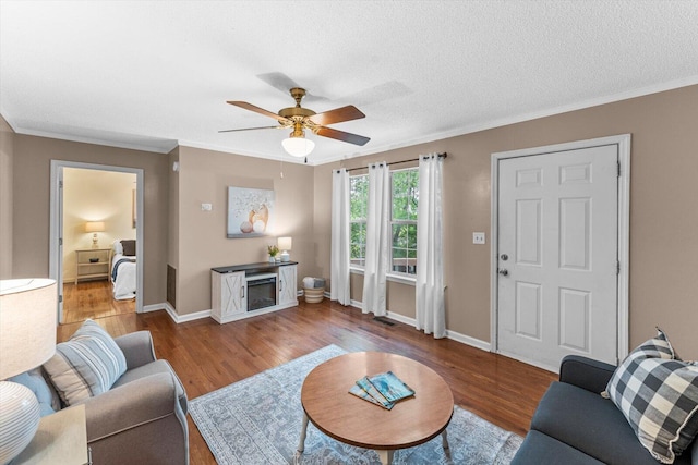 living room featuring a fireplace, crown molding, wood-type flooring, ceiling fan, and a textured ceiling