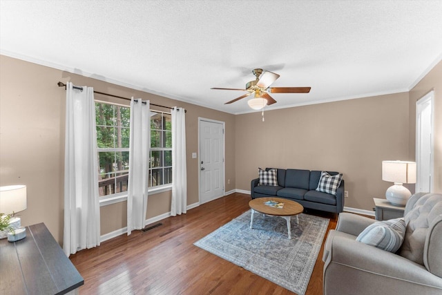 living room featuring a textured ceiling, crown molding, ceiling fan, and dark hardwood / wood-style floors