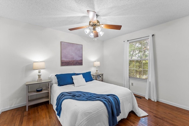 bedroom with ceiling fan, dark hardwood / wood-style floors, and a textured ceiling