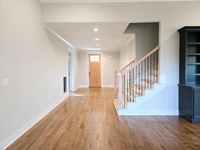 entryway with ornamental molding and hardwood / wood-style floors