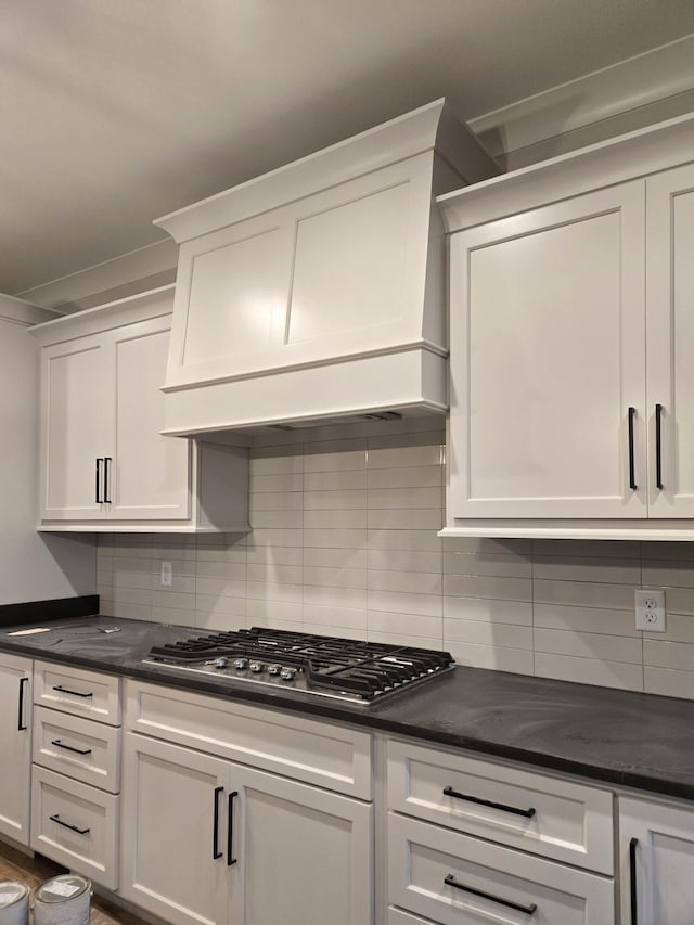 kitchen with premium range hood, backsplash, stainless steel gas cooktop, and white cabinets