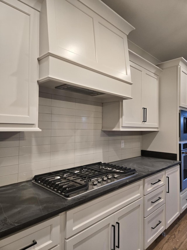 kitchen featuring stainless steel appliances, custom range hood, and white cabinets