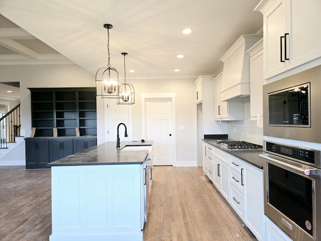 kitchen with appliances with stainless steel finishes, sink, a center island with sink, and white cabinets