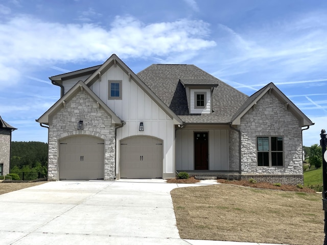 french country style house featuring board and batten siding, concrete driveway, stone siding, roof with shingles, and an attached garage
