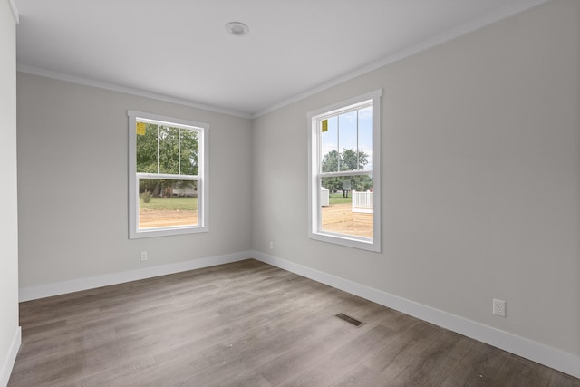 empty room with light hardwood / wood-style floors, crown molding, and a healthy amount of sunlight