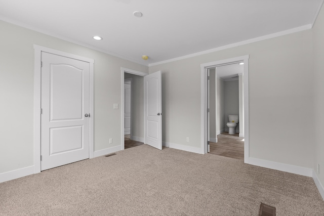 unfurnished bedroom featuring carpet floors, crown molding, and ensuite bathroom