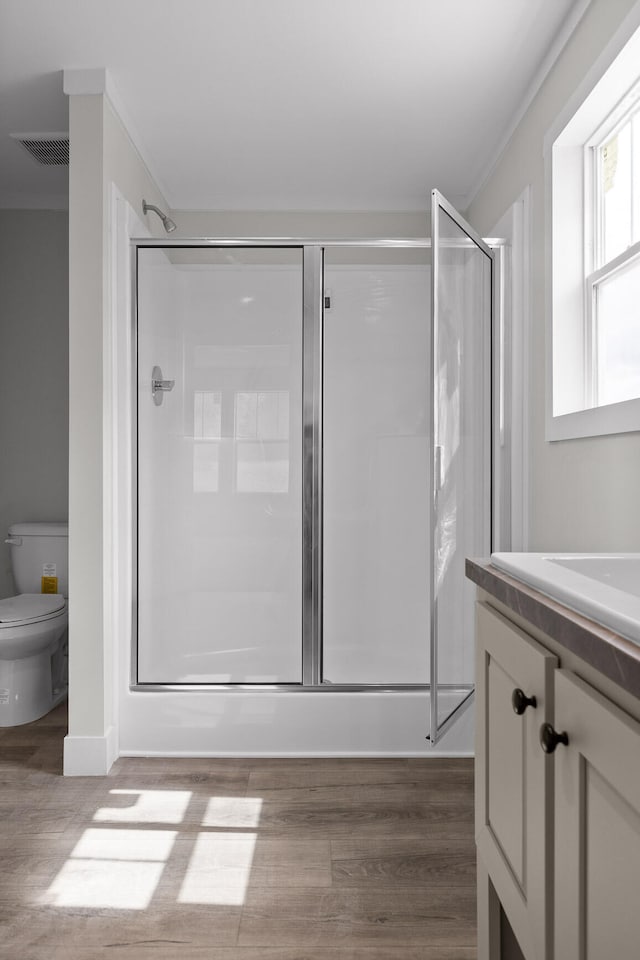 bathroom with vanity, hardwood / wood-style floors, toilet, and a shower with door