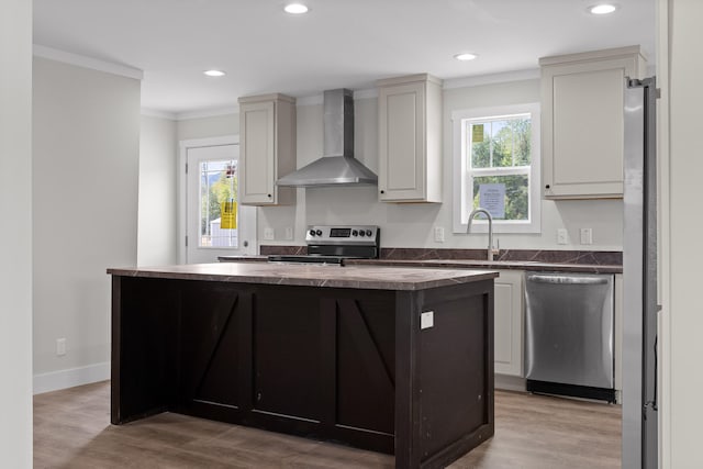 kitchen with wall chimney exhaust hood, plenty of natural light, appliances with stainless steel finishes, and a kitchen island