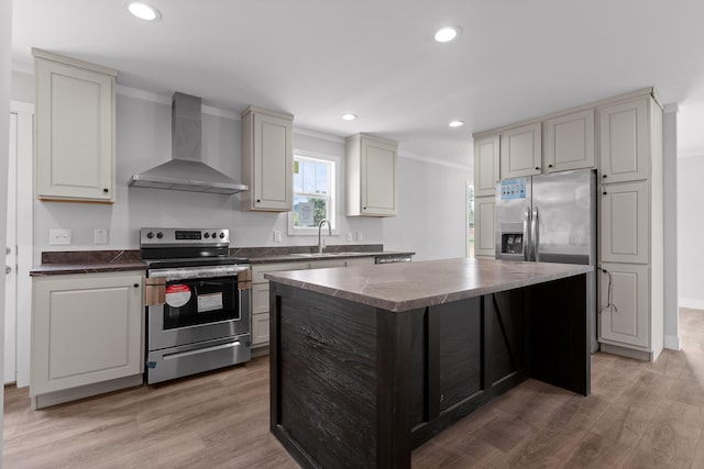 kitchen with wall chimney exhaust hood, wood-type flooring, a kitchen island, ornamental molding, and appliances with stainless steel finishes