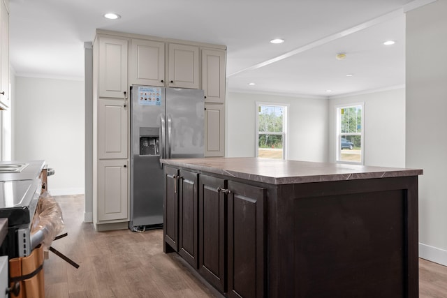 kitchen featuring stainless steel fridge with ice dispenser, crown molding, a kitchen island, and light wood-type flooring