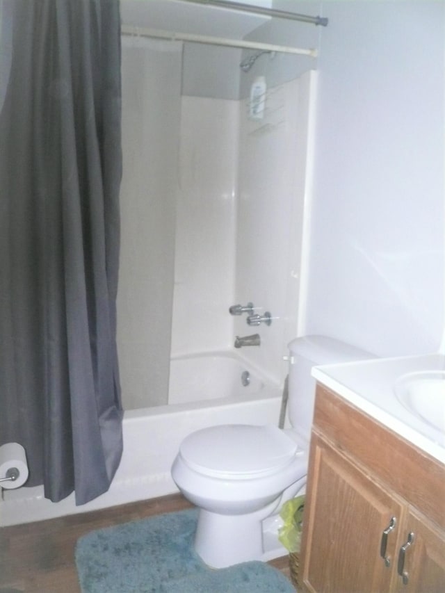 full bathroom with hardwood / wood-style floors, toilet, vanity, and shower / tub combo with curtain