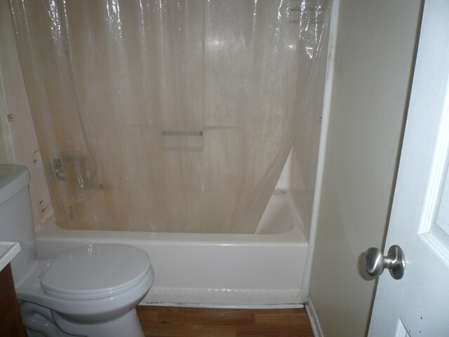 bathroom featuring hardwood / wood-style floors, toilet, and shower / tub combo with curtain