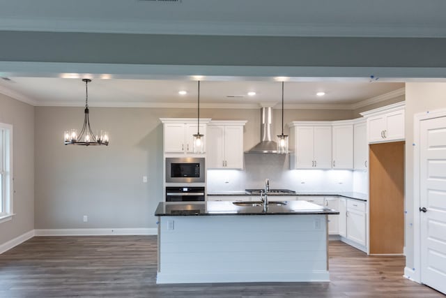 kitchen with a kitchen island with sink, wall chimney range hood, stainless steel appliances, and white cabinetry