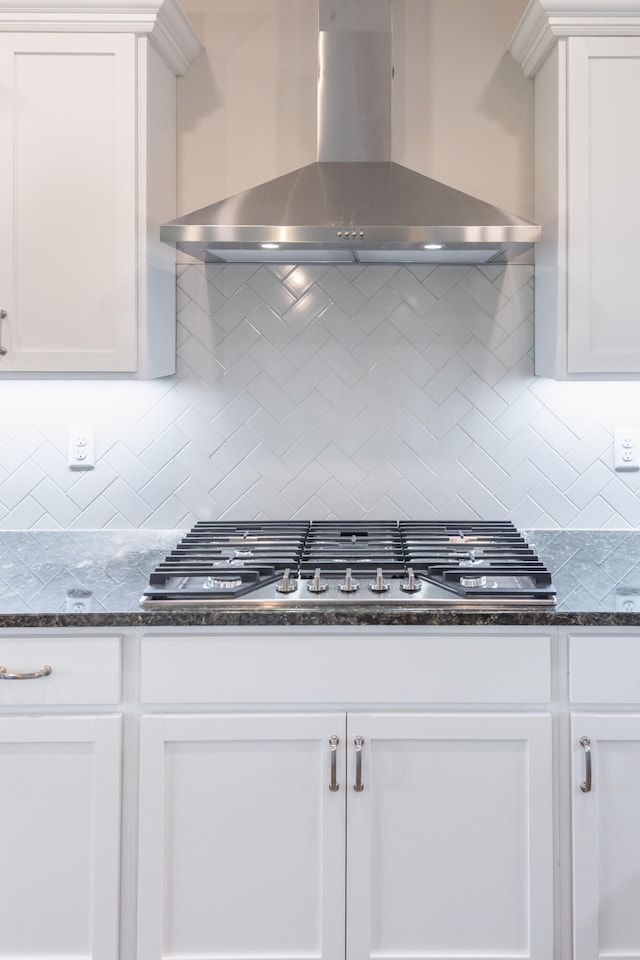 kitchen featuring white cabinets, wall chimney exhaust hood, and backsplash