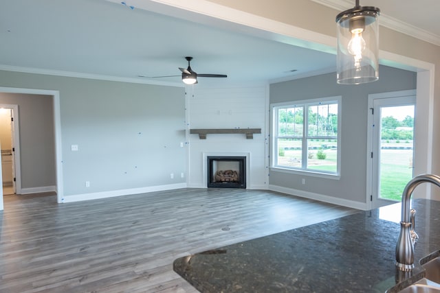 unfurnished living room with ceiling fan, dark hardwood / wood-style floors, and crown molding