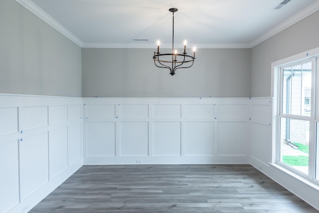 unfurnished dining area with ornamental molding, wood-type flooring, and a notable chandelier