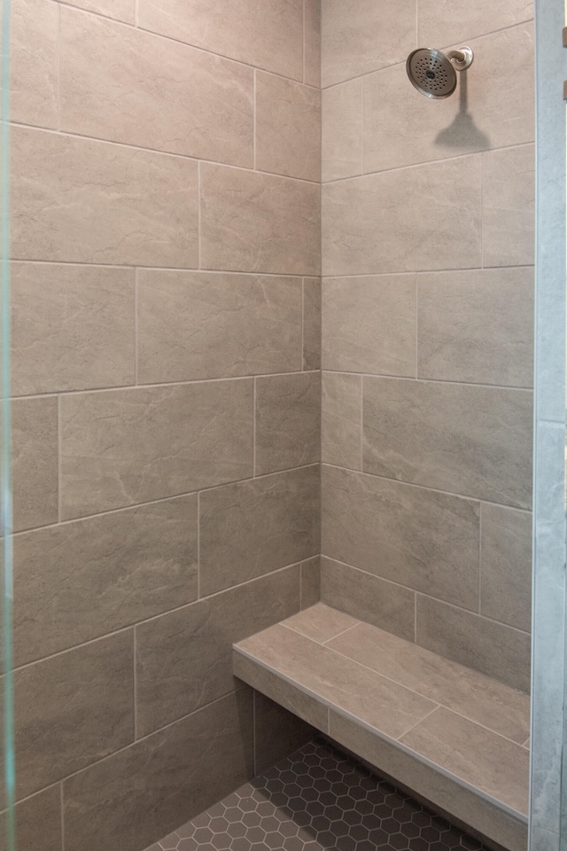 bathroom with a tile shower and tile patterned flooring