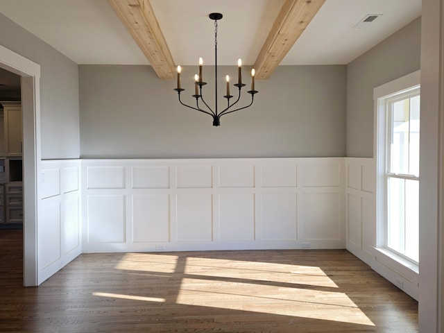 unfurnished dining area with dark hardwood / wood-style floors, beam ceiling, and an inviting chandelier